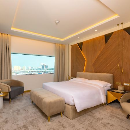 Steigenberger Hotel Doha Exterior photo The photo showcases a modern hotel room with a stylish and contemporary design. It features a spacious layout with a large bed placed in the center, dressed in white linens. Behind the bed is an accent wall made of wood, which adds warmth and texture