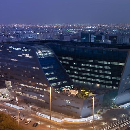 Steigenberger Hotel Doha Exterior photo The image shows a modern architectural building, likely a hotel or office structure, illuminated at night. The design features a unique angular shape with large glass windows, reflecting the surrounding city lights. The building appears to be part of