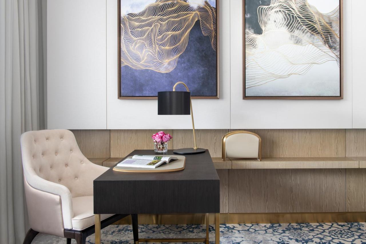 Steigenberger Hotel Doha Exterior photo The photo depicts a stylish office or study area. In the foreground, there is a dark wooden desk with a few items on it, including a notepad and a small vase of flowers. A modern black lamp is placed on the desk, providing a sophisticated touch. 

Ad