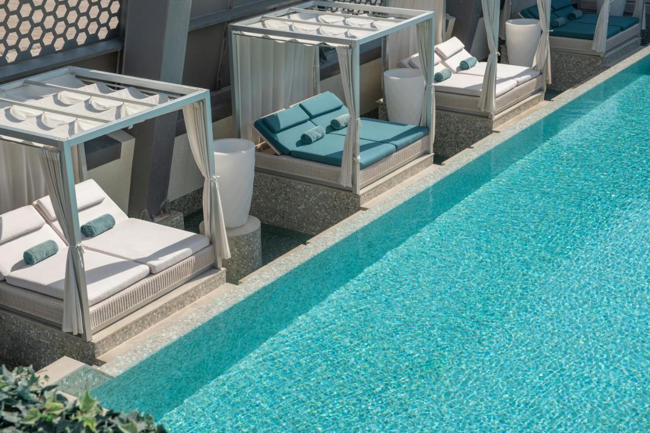 Steigenberger Hotel Doha Exterior photo The photo shows a luxurious pool area with several stylish cabanas placed alongside a clear, blue swimming pool. Each cabana features comfortable lounge chairs with cushions, and there are white planters nearby. The overall design conveys a serene an
