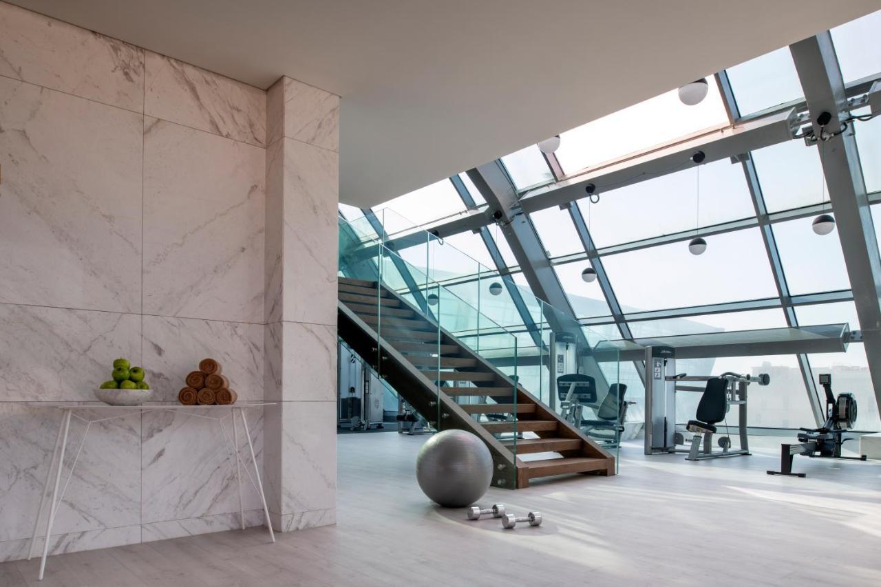 Steigenberger Hotel Doha Exterior photo The photo showcases a modern, stylish interior space, likely a gym or fitness area. Key features include:

- **Large Windows**: The room is filled with natural light due to its expansive glass walls and ceiling.
- **Staircase**: A wooden staircase le