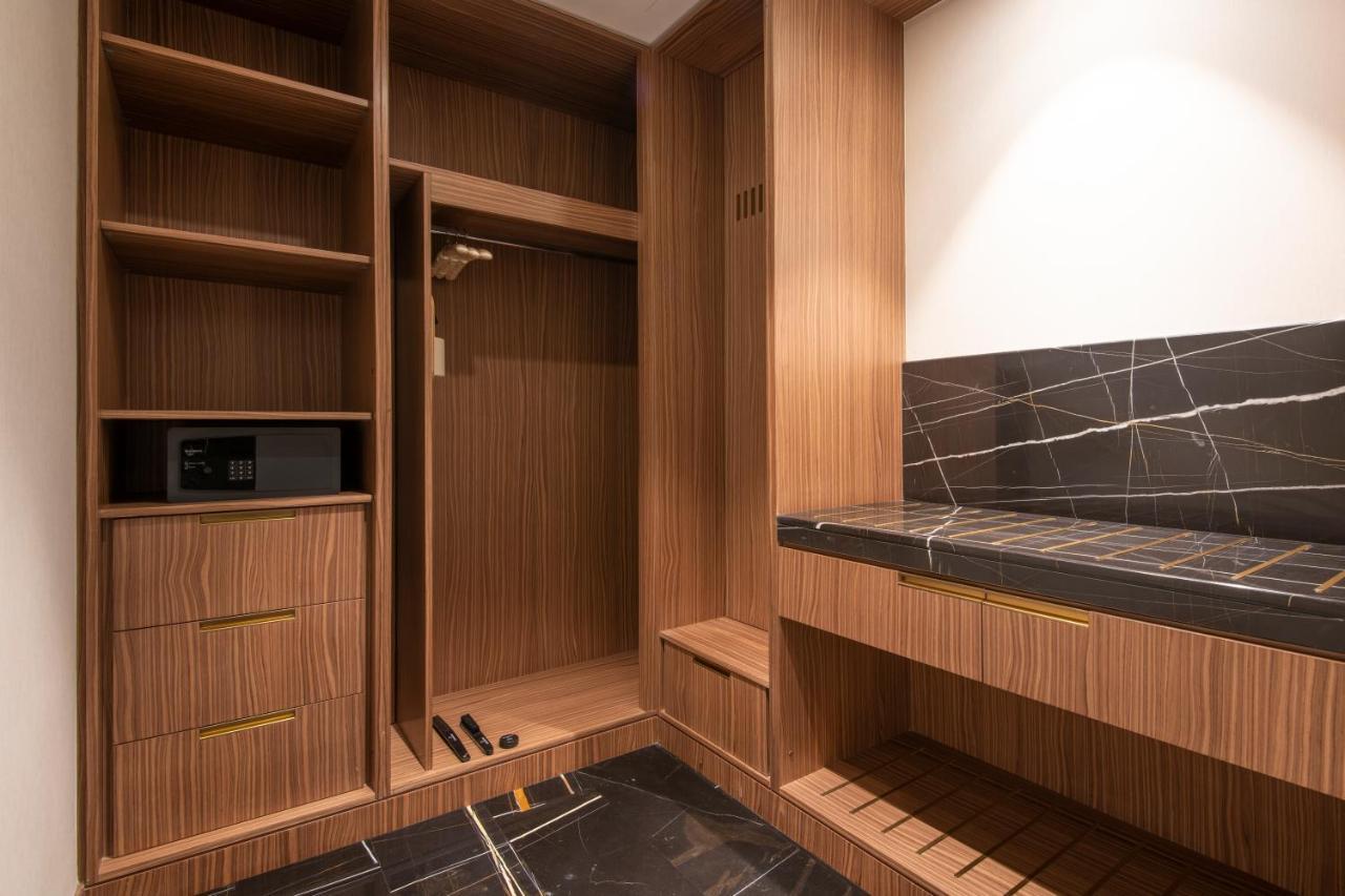 Steigenberger Hotel Doha Exterior photo The photo shows a stylishly designed closet or wardrobe area. It features wooden panels with a warm finish. On the left side, there are open shelves, as well as a section for hanging clothes. Below, there are two drawers, adding extra storage space. 