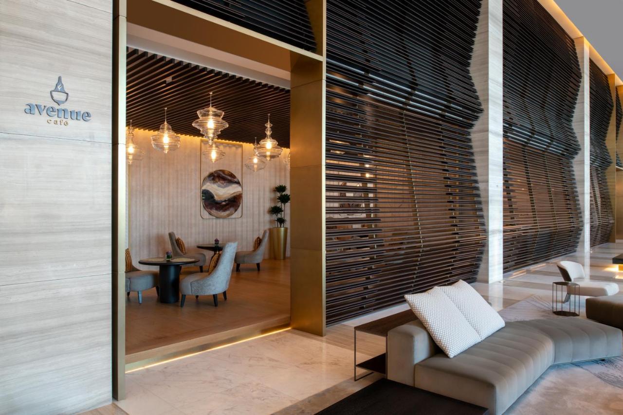 Steigenberger Hotel Doha Exterior photo The photo shows a modern and elegant interior space of a café or restaurant. There is a large entrance framed in gold that leads into the café area, which features stylish furniture. Inside, you can see several chairs and tables, along with decorativ