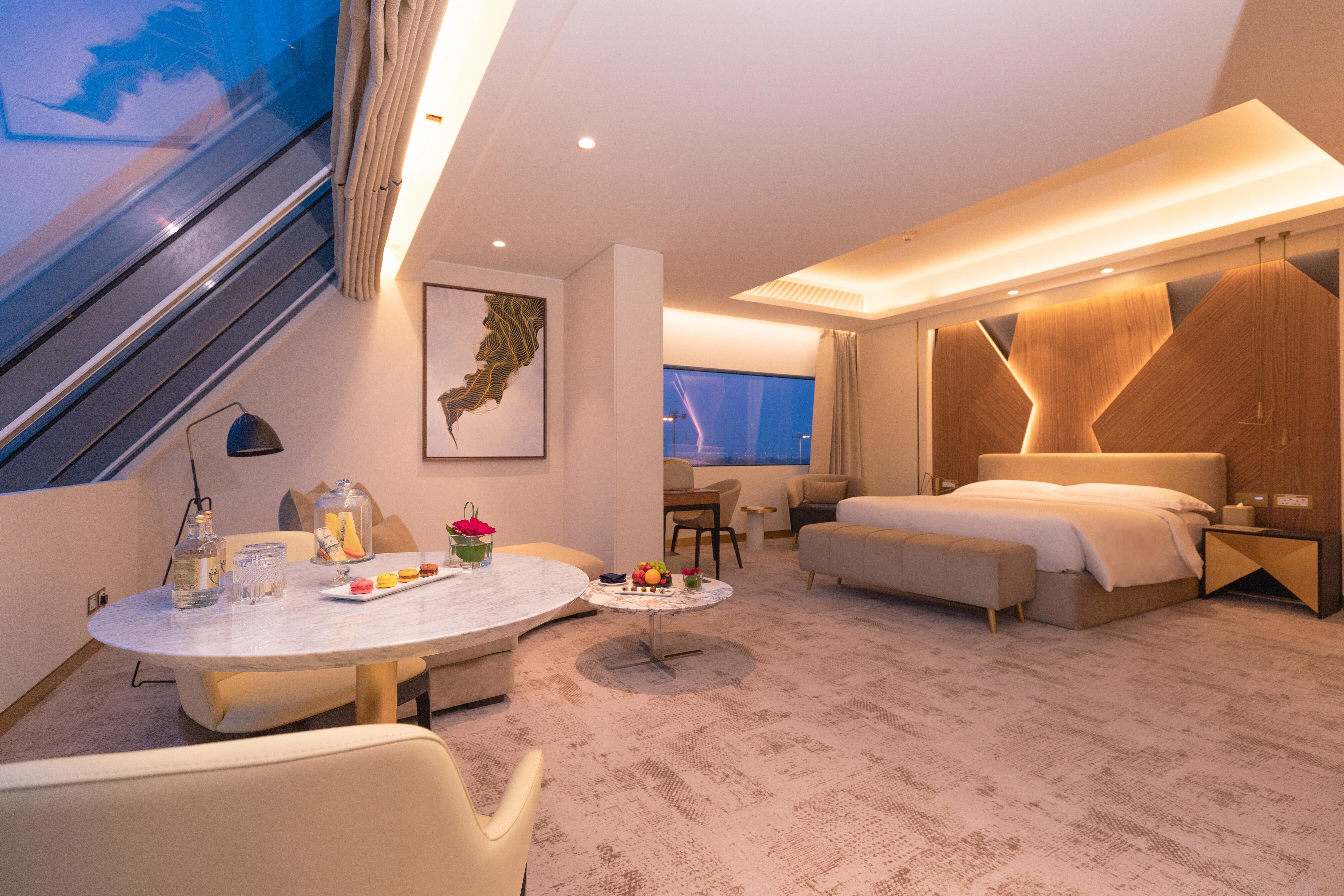 Steigenberger Hotel Doha Exterior photo The photo shows a modern hotel room featuring a spacious layout with minimalist decor. The room includes a large bed with elegant bedding, soft lighting, and contemporary furnishings. A seating area with a small table and chairs is present, along wit