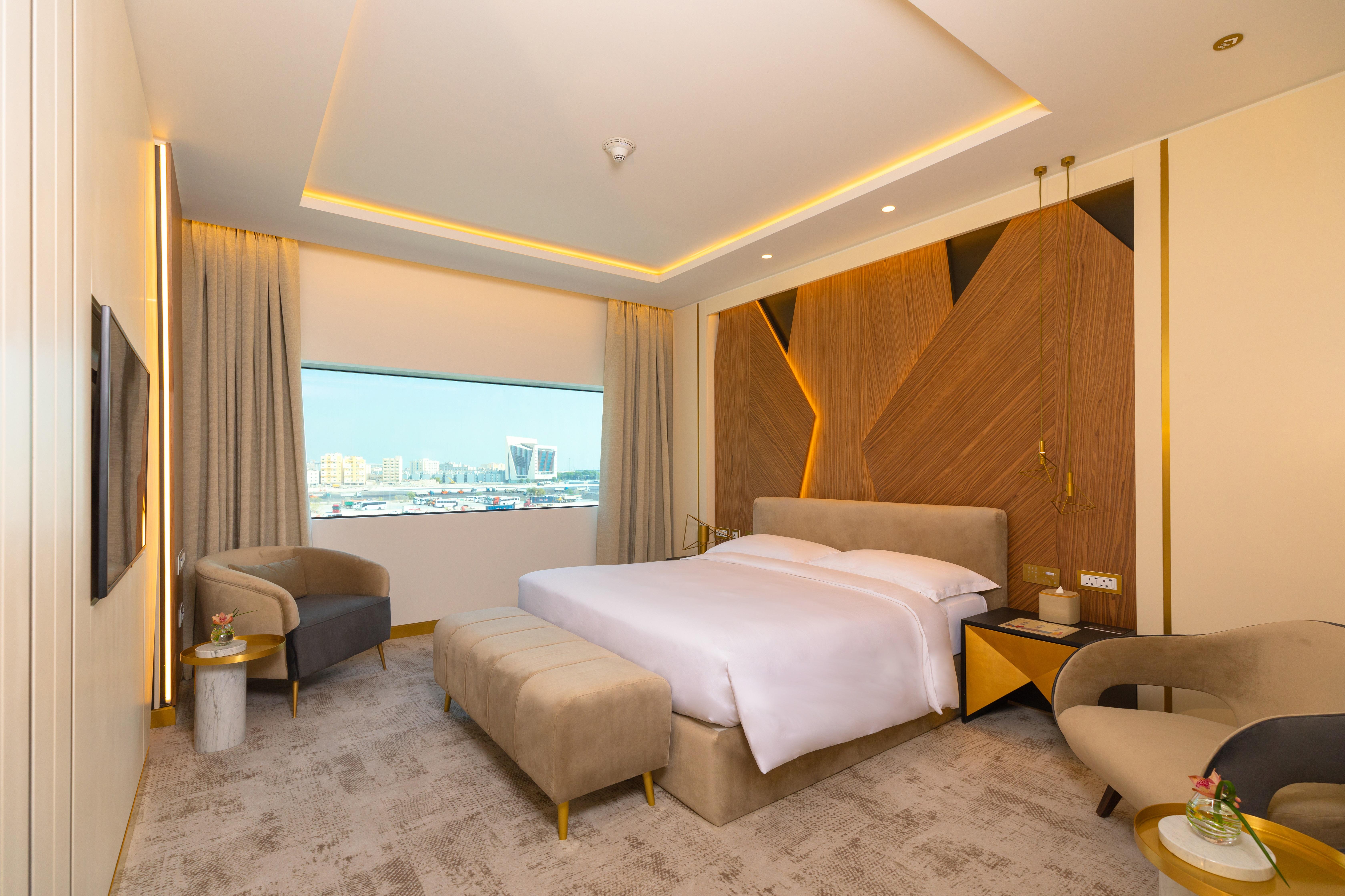 Steigenberger Hotel Doha Exterior photo The photo showcases a modern hotel room with a stylish and contemporary design. It features a spacious layout with a large bed placed in the center, dressed in white linens. Behind the bed is an accent wall made of wood, which adds warmth and texture