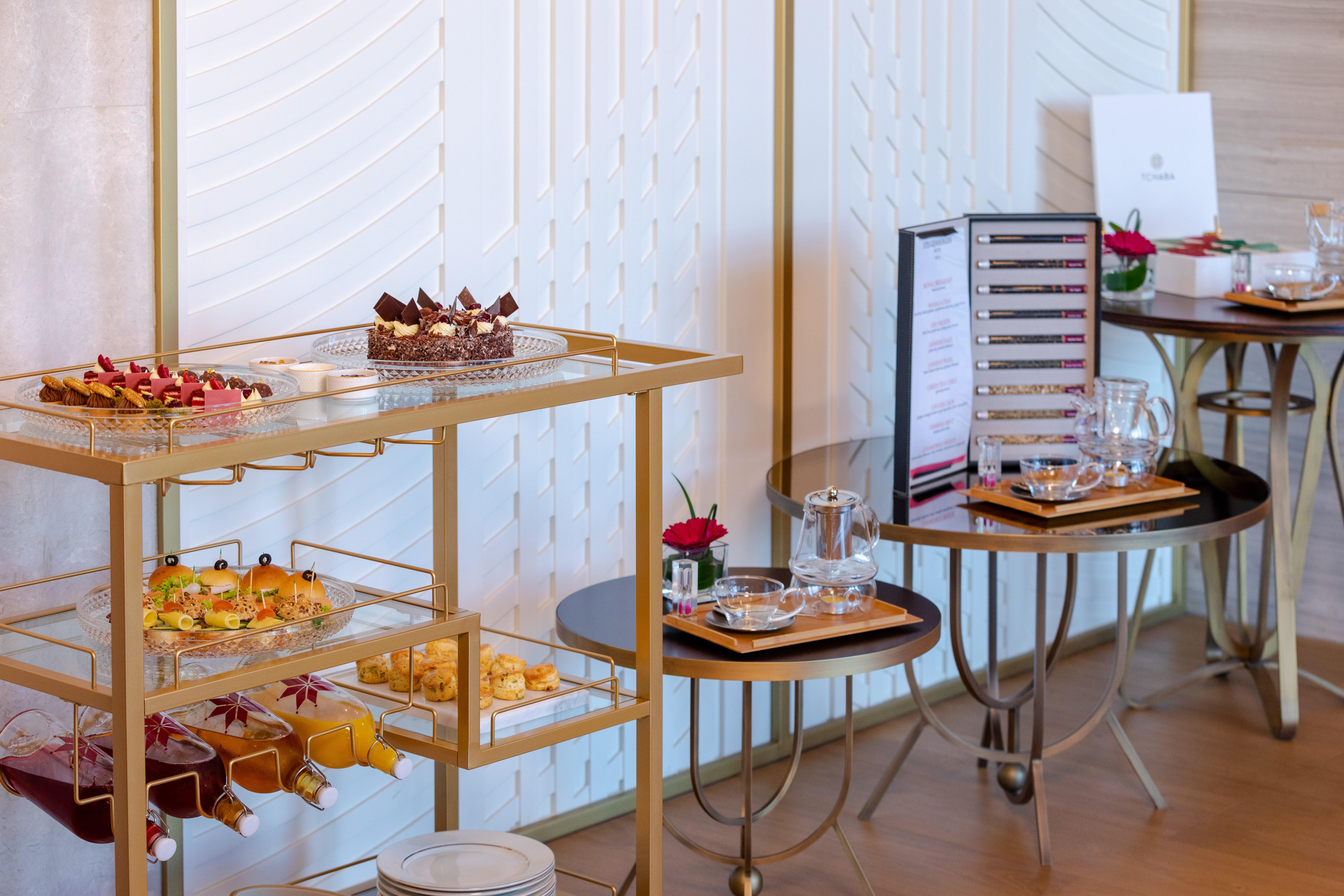 Steigenberger Hotel Doha Exterior photo The photo shows a beautifully arranged buffet table featuring a variety of desserts and snacks. There is a gold cart displaying an assortment of pastries and small treats, including colorful hors d'oeuvres and mini desserts, likely for a high-end eve
