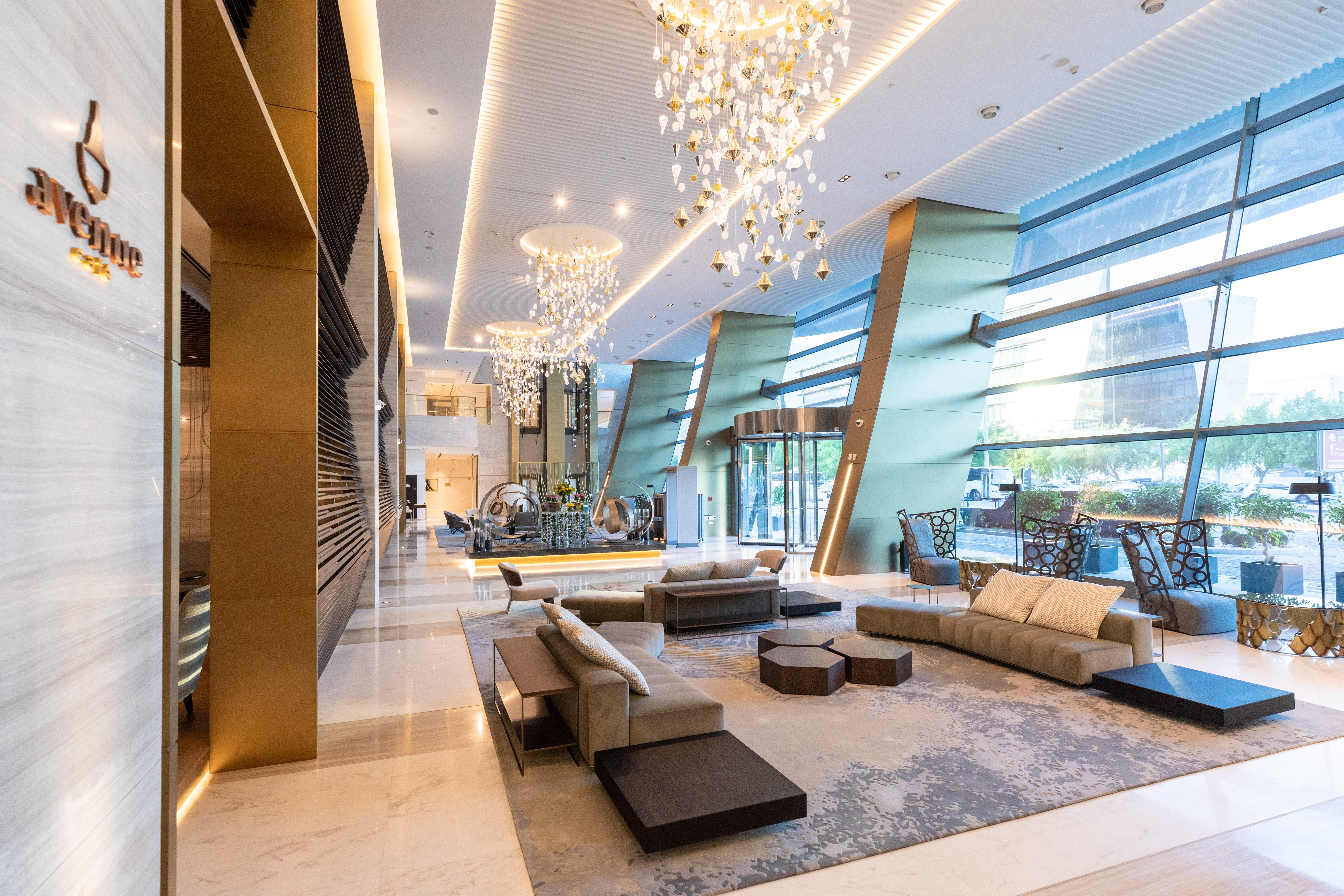 Steigenberger Hotel Doha Exterior photo The photo shows a modern and elegant hotel lobby. It features stylish furniture, including sofas and coffee tables, arranged in a welcoming layout. The space is well-lit by several large chandeliers hanging from the ceiling, adding a touch of luxury.
