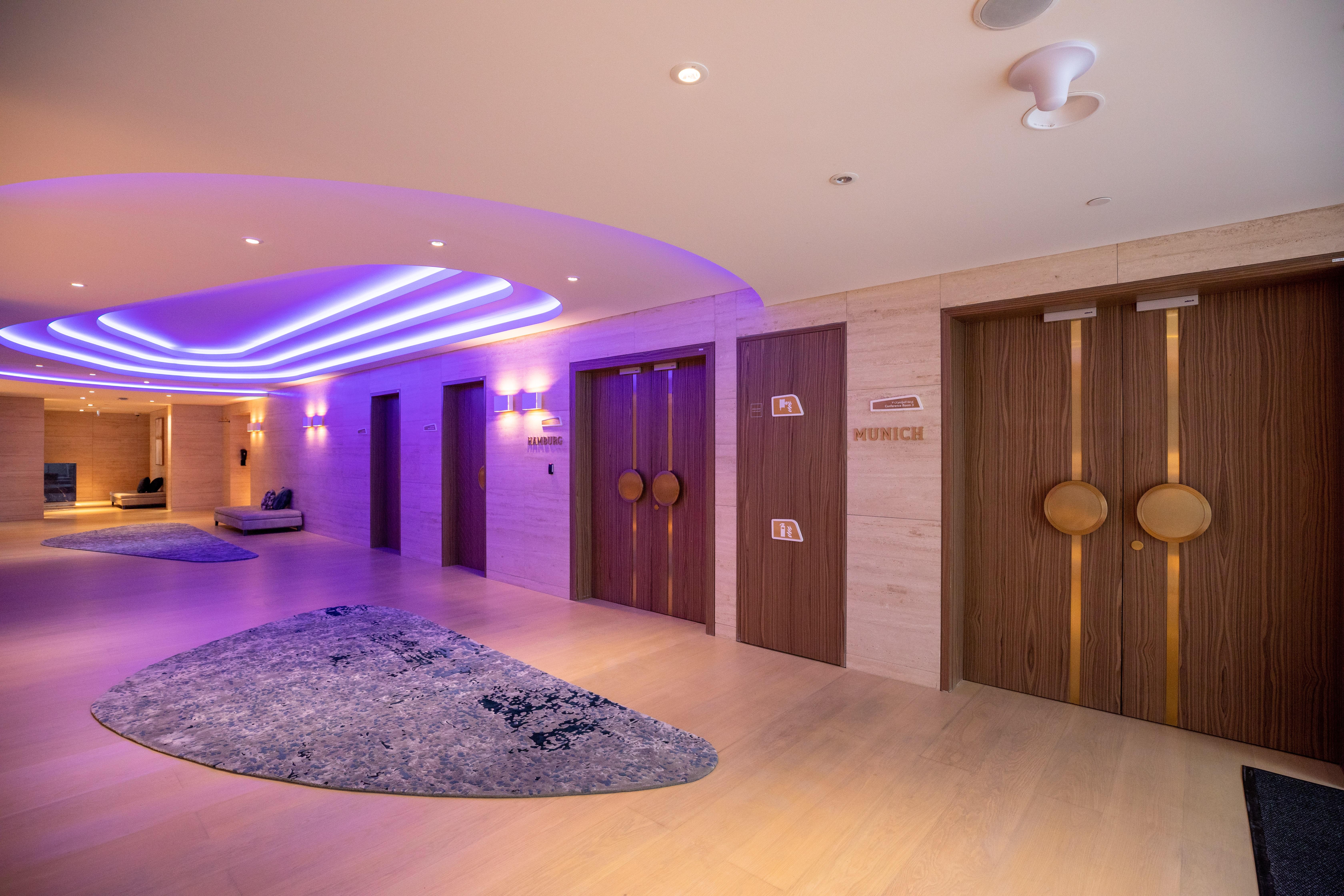 Steigenberger Hotel Doha Exterior photo The photo shows a modern interior space, likely a hotel or spa. There are two prominent wooden doors with circular handles, which could be entrances to different facilities. The walls are adorned with subtle lighting, creating a warm and inviting amb