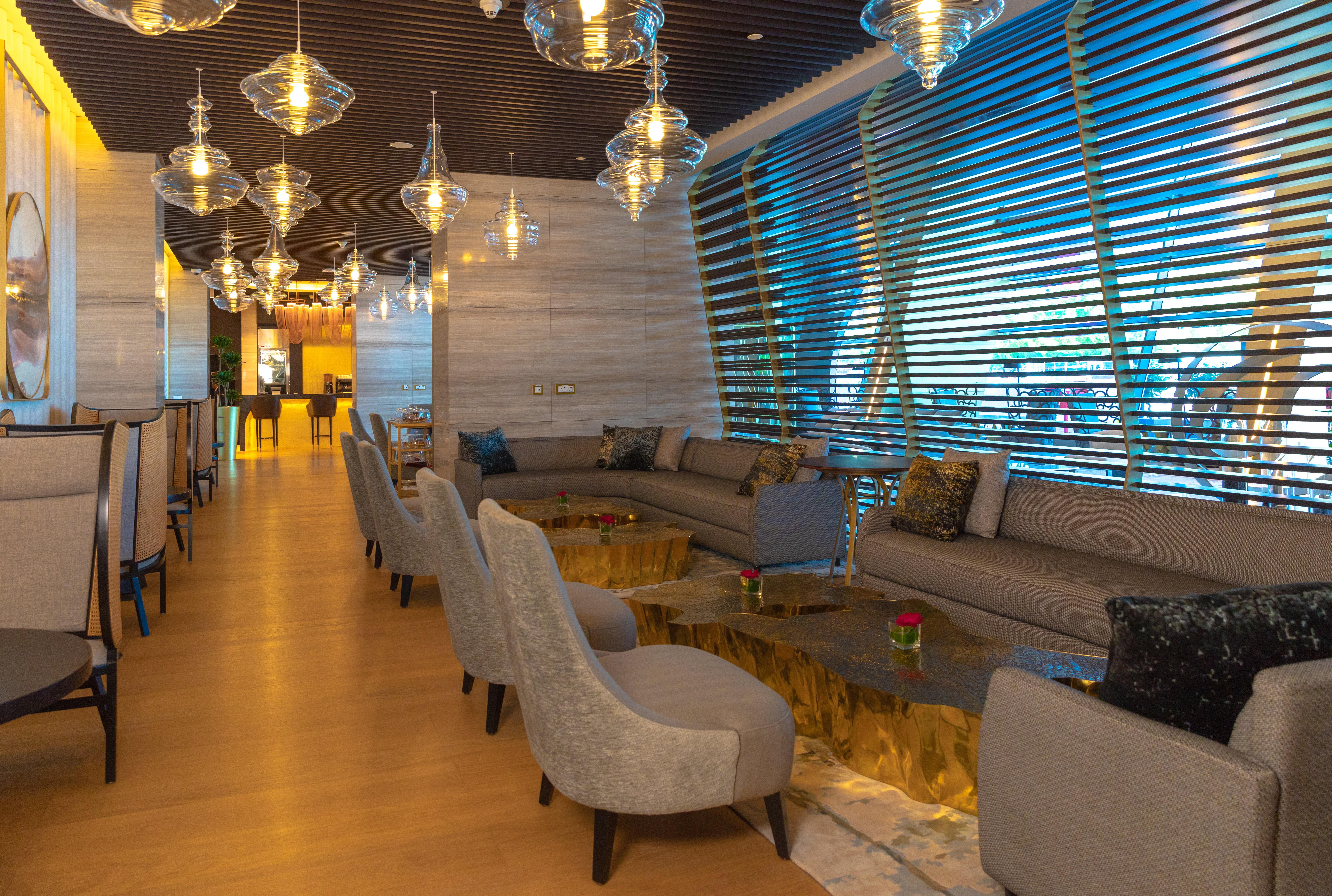 Steigenberger Hotel Doha Exterior photo The photo depicts a modern and stylish lounge area. It features a spacious layout with comfortable seating arrangements, including beige sofas and stylish chairs. The tables have a unique design, with a gold-colored base. Ambient lighting is provided