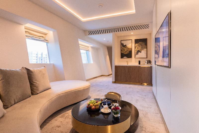 Steigenberger Hotel Doha Exterior photo The photo shows a modern and stylish interior space, likely a lounge or a living area. It features a curved sofa in a light color, providing a comfortable seating arrangement. In the center, there is a round coffee table adorned with a selection of f