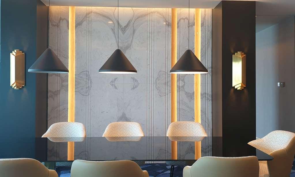 Steigenberger Hotel Doha Room photo The photo showcases a modern interior space featuring a sleek design. The focal point is a wall adorned with a marble-like texture, enhanced by vertical lighting strips that add warmth to the environment. Above a table or counter are three pendant li